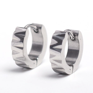 Détail de boucles d'oreilles créoles en acier argenté avec texture géométrique rainurée
