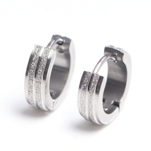 Close-up of silver steel hoop earrings with textured glitter finish and parallel stripes