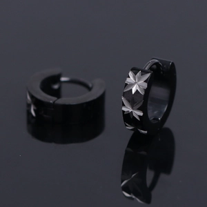 Matte black stainless steel huggie earrings with engraved star patterns on dark surface