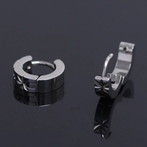 Detail of silver stainless steel hoop earrings featuring engraved star patterns and clasp