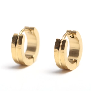 Close-up of golden stainless steel huggie earrings with vertical groove texture