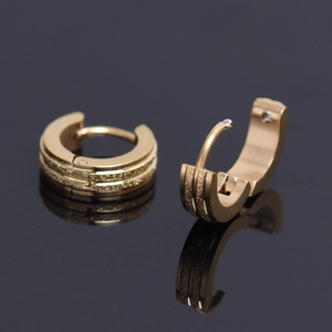 Close-up of golden huggie earrings with textured matte stripes and hinge closure