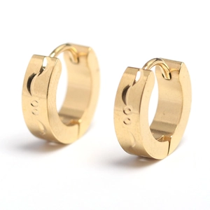 Détail macro de boucles d'oreilles huggie dorées avec motifs de lune gravés et points