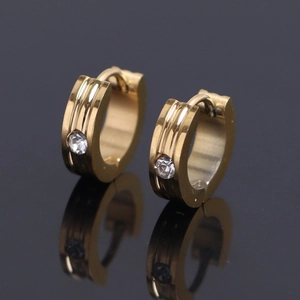 Vue détaillée de boucles d'oreilles huggie dorées en acier avec un oxyde de zirconium