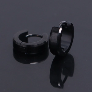Close-up of black polished stainless steel hoop earrings with reflection on dark surface