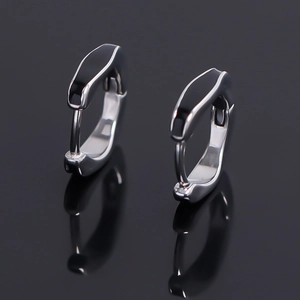 Close-up of silver hoop earrings with black enamel inlay on reflective dark background