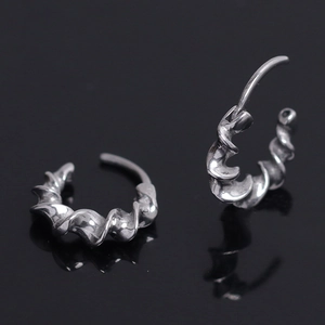 Close-up of silver twist hoop earrings featuring a luxury spiral textured metal design