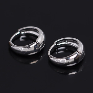 Polished silver copper hoop earrings for men in minimalist huggie style on black reflection
