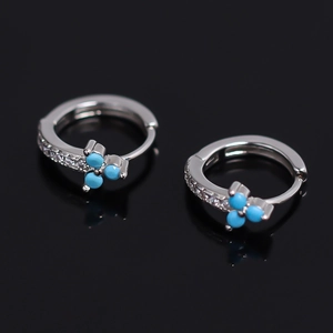 Créoles en cuivre argenté avec pierres turquoise et zircons sur fond noir réfléchissant