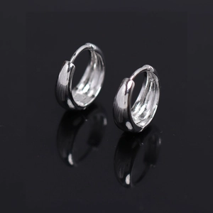 Polished silver minimalist hoop earrings for men on a black reflective background