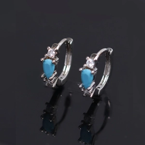 Silver drop earrings with pear-cut turquoise stones and zircon accents on black background