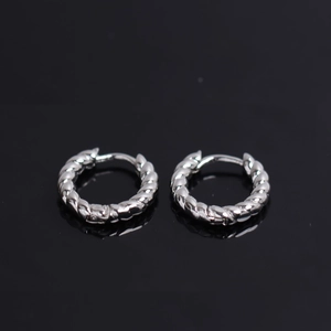 Macro shot of silver twisted hoop earrings with a polished finish on black mirror surface