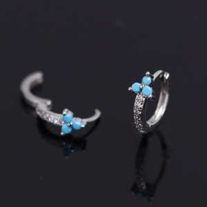 Vue détaillée des boucles d'oreilles huggie en argent avec fleurs turquoise et zircons