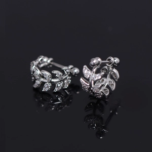 Fashionable silver leaf hoop earrings with micro-set zircons on a reflective black surface