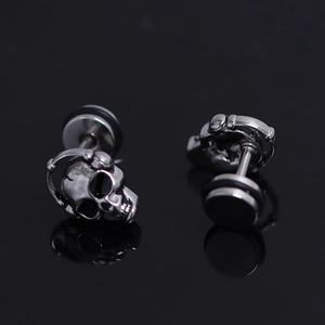 Macro detail of gothic skull stud earrings with headphones and flat-back screw ear plugs