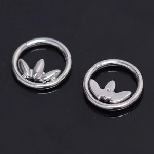 Pair of lotus and butterfly stainless steel clicker earrings on black background