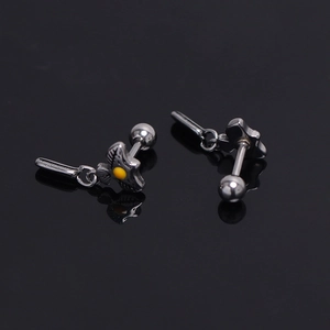 Macro detail of stainless steel eagle wing ear studs with a yellow center accent