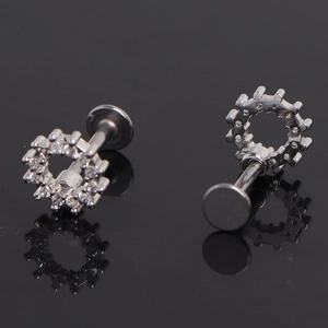 Macro detail of silver gear-shaped ear studs with micro-pave cubic zirconia stones