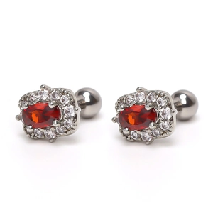 Close-up of barbell earrings with oval red ruby stone and white diamond halo in silver