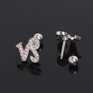 Silver Capricorn zodiac stud earring with white zircons on a black reflective surface