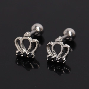 Macro shot of silver crown earrings with black zircon stones on a dark background