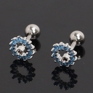 Détail macro du piercing d'oreille en argent avec zircons bleus et fermeture à vis sphérique