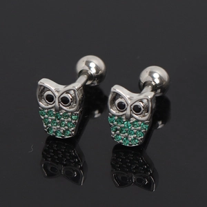Gros plan de boucles d'oreilles chouette avec zircons verts et fermoir à vis sur fond noir