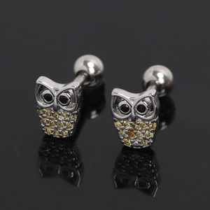 Détail macro de boucles d'oreilles hibou en acier inoxydable avec cristaux jaunes et billes