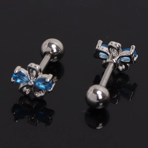 Vue macro de boucles d'oreilles fleur en acier, zircons bleus et fermoirs à vis à bille