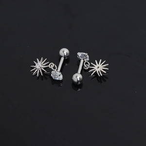 Macro detail of stainless steel star earrings with clear zircons on black surface