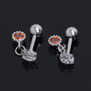 Détail de boucles d'oreilles en acier avec zircon orange et base florale argentée