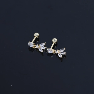Boucles d'oreilles fleur dorée avec zircons marquise sur une surface noire réfléchissante