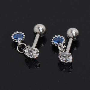 Détail du piercing barbell en acier avec cristal bleu et pierre de zircon blanc suspendue