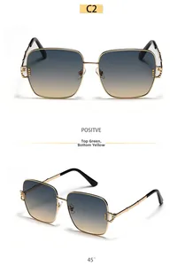 Detail of oversized square gold metal sunglasses with gradient green to yellow lenses