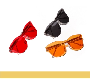 Flat lay of rimless oversized sunglasses in red, black, and orange with modern resin lenses