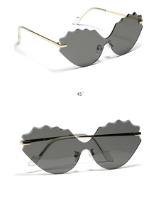 Detail of rimless cat-eye sunglasses with wavy grey lenses and gold metal temples