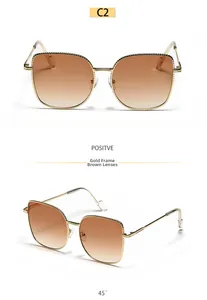 Detailed view of oversized gold metal cat-eye sunglasses with brown gradient lenses