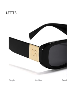 Close-up of black square sunglasses featuring a golden metal letter G hinge detail