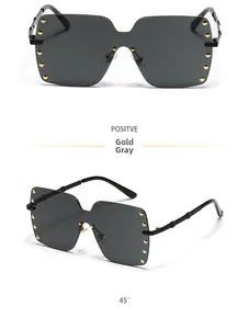 Oversized rimless square sunglasses featuring gold studs and grey lenses at 45 degree angle