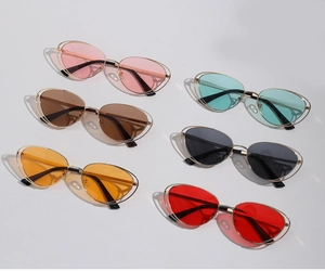 Flat lay of six cat-eye metal frame sunglasses with multi-color lenses on grey background