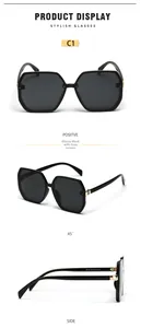 Detailed close-up of oversized black hexagonal sunglasses with golden metal hinges and CE marks