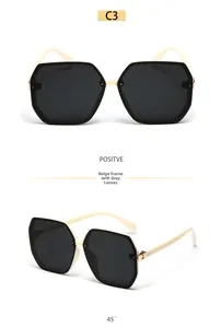 Detail view of beige polygon oversized sunglasses with grey lenses and gold accents