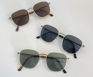 Detailed view of three vintage square sunglasses in brown, black, and green with gold frames