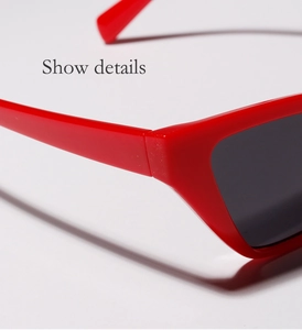 Detailed close-up of the red frame hinge and dark lens of these cat-eye sunglasses