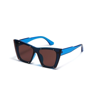 Occhiali da sole cat-eye stile punk con montatura blu, lenti scure e dettagli in rivetti