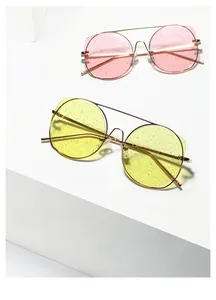 Détail de montures métalliques oversize avec verres scintillants roses et jaunes sur socle