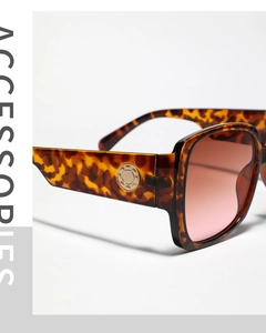 Détail de lunettes de soleil carrées en écaille avec verres dégradés roses et clous dorés