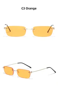Détail de lunettes de soleil rectangles sans monture avec verres orange et branches dorées