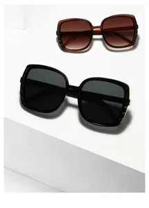 Modern square sunglasses in black and brown with sleek gold accents on geometric display