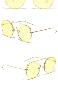 Détails de lunettes de soleil en métal doré avec verres jaunes pailletés et bords coupés